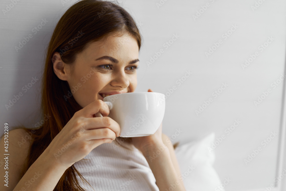 happy woman with a cup of coffee and lies in bed and looks to the side close-up happy woman with a cup of coffee and lies in bed and looks to the side close-up