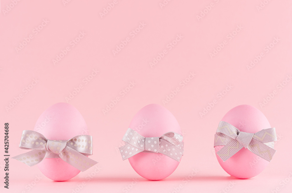 Pink easter eggs with grey bows standing in row on pastel pink background. Pink easter eggs with grey bows standing in row on pastel pink background.