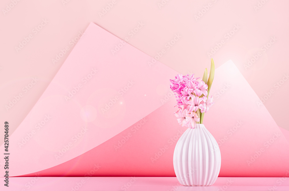 Bright delicate spring white hyacinth bouquet in ceramic vase with sunlight, sun flare on pastel pink geometric background in contempory style, copy space. Festive backdrop for wedding. Bright delicate spring white hyacinth bouquet in ceramic vase with sunlight, sun flare on pastel pink geometric background in contempory style, copy space. Festive backdrop for wedding.