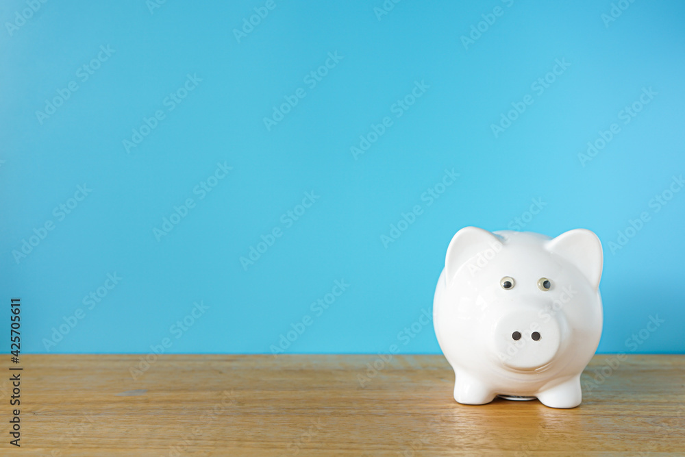 Fototapeta premium White Piggy bank on blue background with copy space 