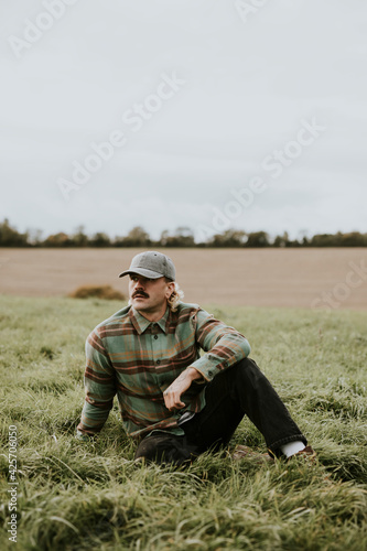 Urban man in a cap chilling on the grass field