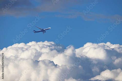 Airplane flying in the blue sky above the white clouds. Commercial plane at flight, travel concept