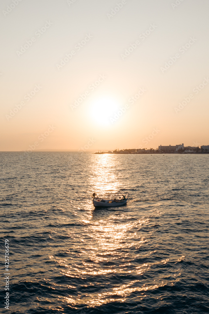 Boat in the sea near Cyprus shore on the sunset with a port bay in the background