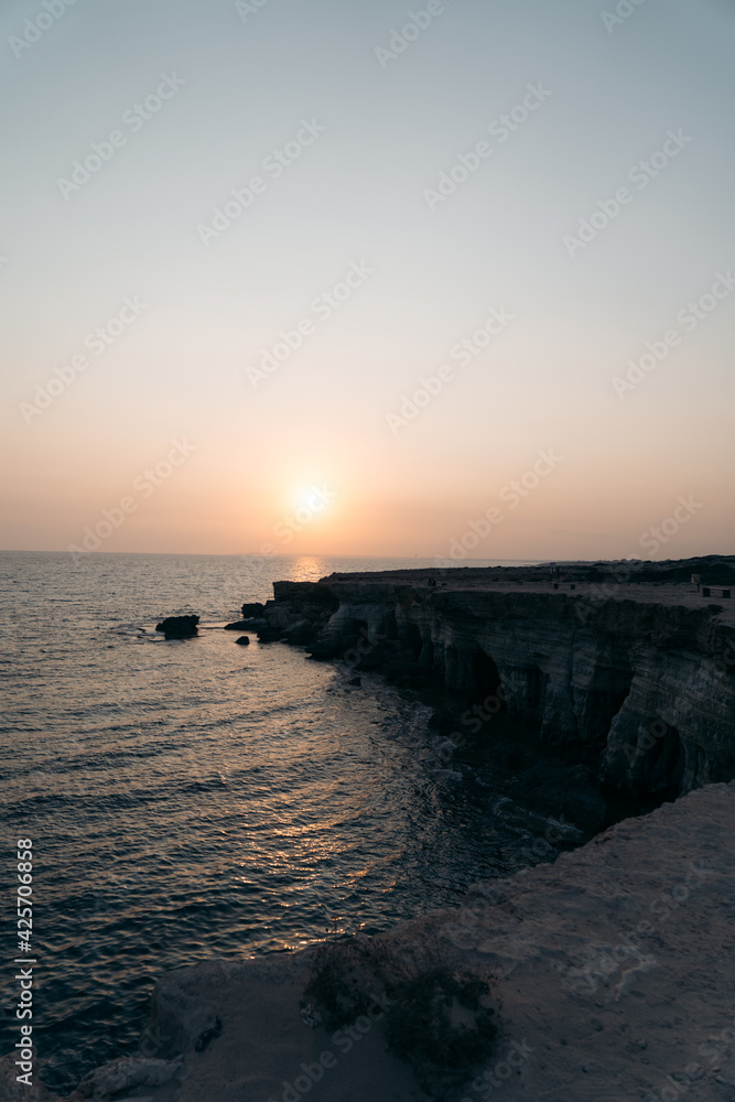 Sunset view on the coast in Cyprus with cliffs and rocks on the background