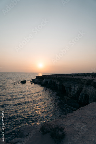 Sunset view on the coast in Cyprus with cliffs and rocks on the background