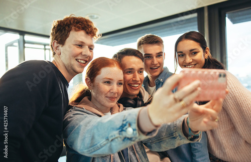 Smiling students clicking selfies in high school © Jacob Lund