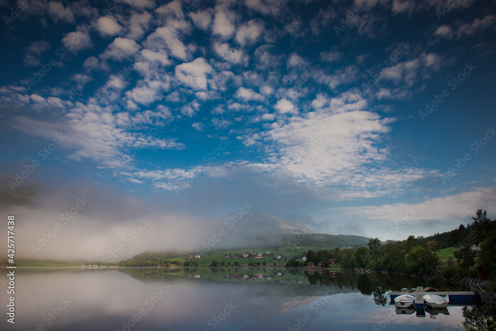 Fototapeta premium Dawn over the water. Fog over the lake. Fishing boats at the pier. Peace and serenity of the morning