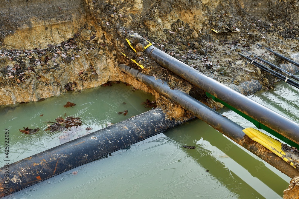 Frozen Construction Site: Water-Filled Excavation Pit with Industrial Pipes in Winter Conditions Frozen Construction Site: Water-Filled Excavation Pit with Industrial Pipes in Winter Conditions
