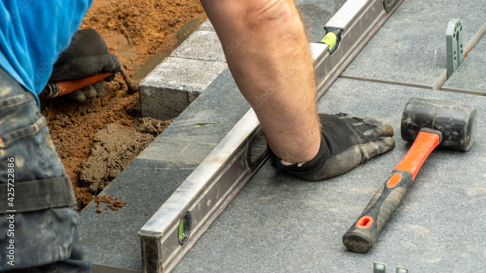 Expert workman laying patio edging bricks in garden makeover Expert workman laying patio edging bricks in garden makeover