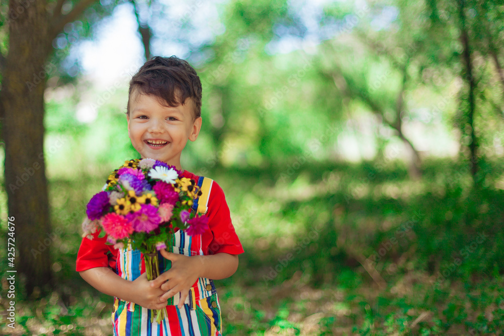 Laughing boy with a bouquet of wild flowers in his hands against the background of nature. Mother's Day. Laughing boy with a bouquet of wild flowers in his hands against the background of nature. Mother's Day.