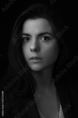 Black and white portrait of young brunette woman in a studio on a black background