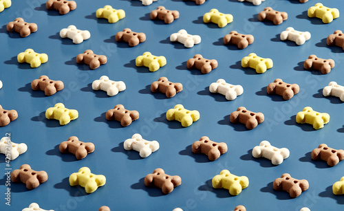 Pattern of bone-shaped dog biscuits. White, brown and yellow on blue background