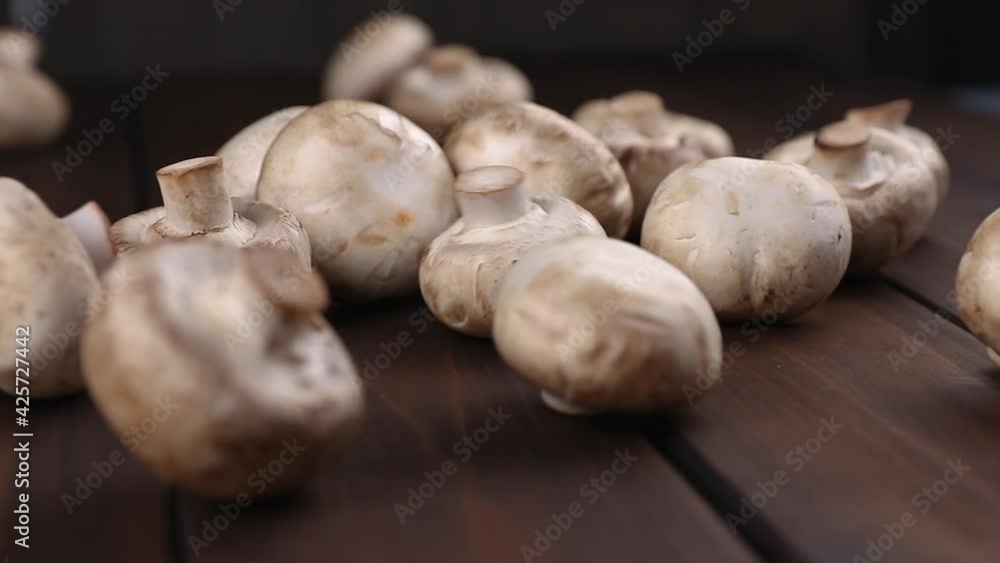 raw porcini champignon mushrooms falling down on a wooden cutting board and kitchen background close-up raw porcini champignon mushrooms falling down on a wooden cutting board and kitchen background close-up