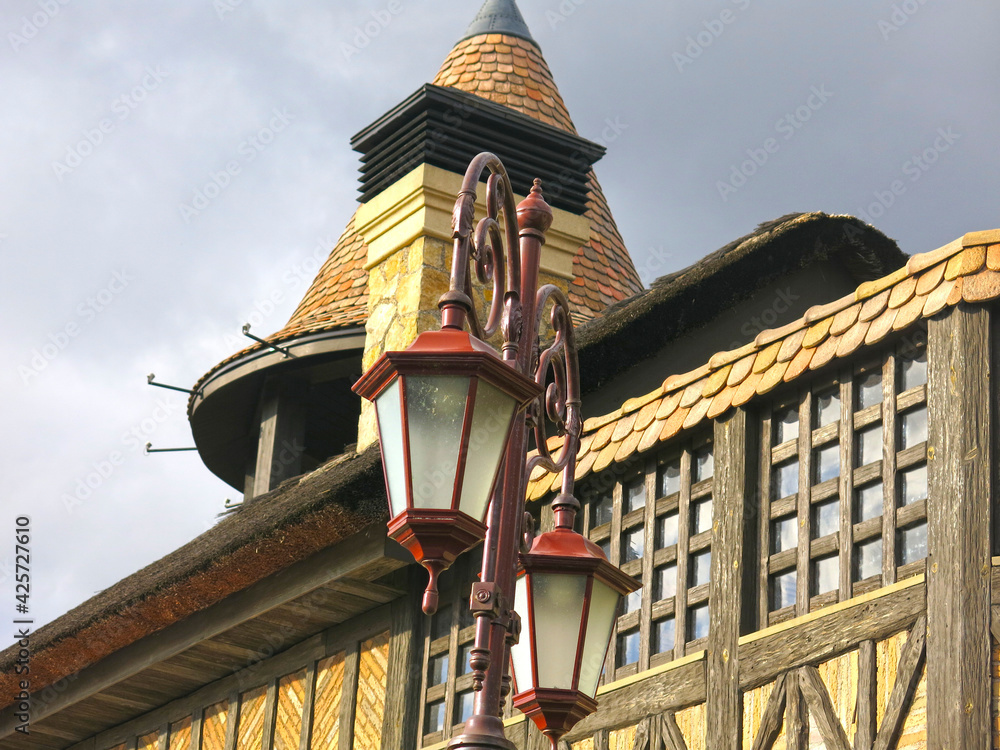 an old lantern in front of a half-timbered building, a medieval painting