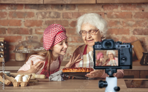 Little granddaughter with granny enjoying homemade fruit pie