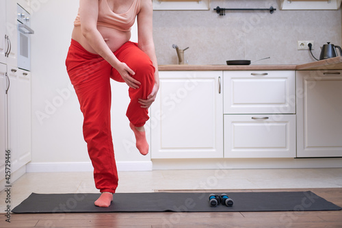 Yoga at home during pregnancy and problems with getting a knee injury. Pregnant woman on Vorkuta holds on to a sprain on her leg photo