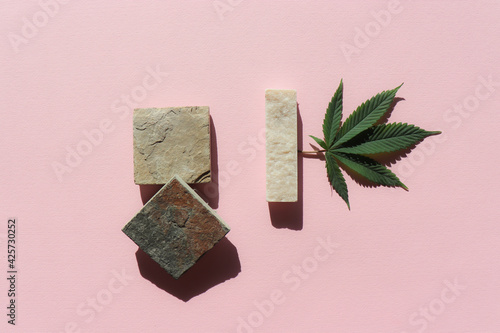 Fototapeta Naklejka Na Ścianę i Meble -  Cannabis green leave and a natural stone marble geometrical quadrature and rectangle shapes on a pink background. Minimal cannabis monochromatic contemporary modern concept.