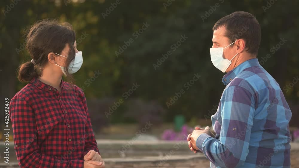 Happy family talking on park bench during coronavirus crisis.Social distancing, virus protection.Happy People in medical safety mask.Child, father wearing safety mask in park. Family concept, epidemic Happy family talking on park bench during coronavirus crisis.Social distancing, virus protection.Happy People in medical safety mask.Child, father wearing safety mask in park. Family concept, epidemic