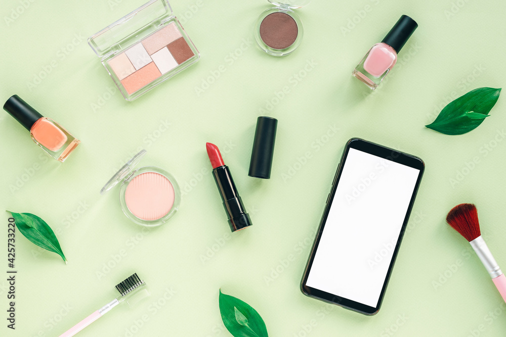 Makeup cosmetic products and mobile phone with blank screen on light green background. Top view, flat lay Makeup cosmetic products and mobile phone with blank screen on light green background. Top view, flat lay