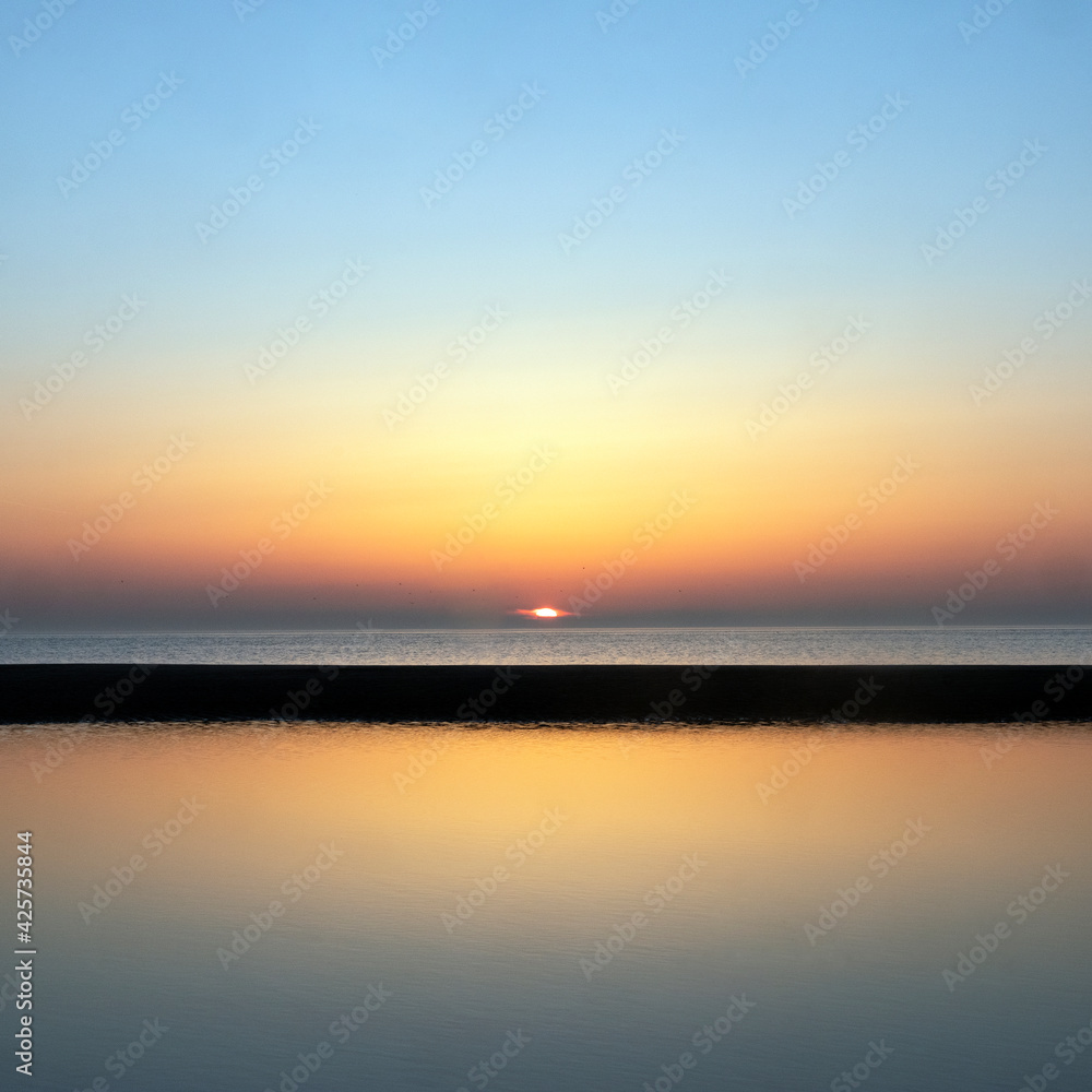 reflection of colorful sunset in water near beach