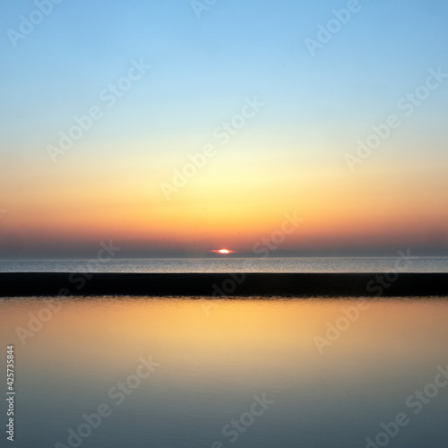 reflection of colorful sunset in water near beach © ahavelaar