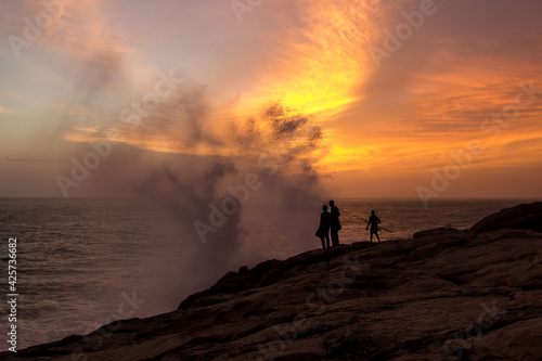 Water aerosol spraying in the air after Powerful waves hitting rocks at sunset, India