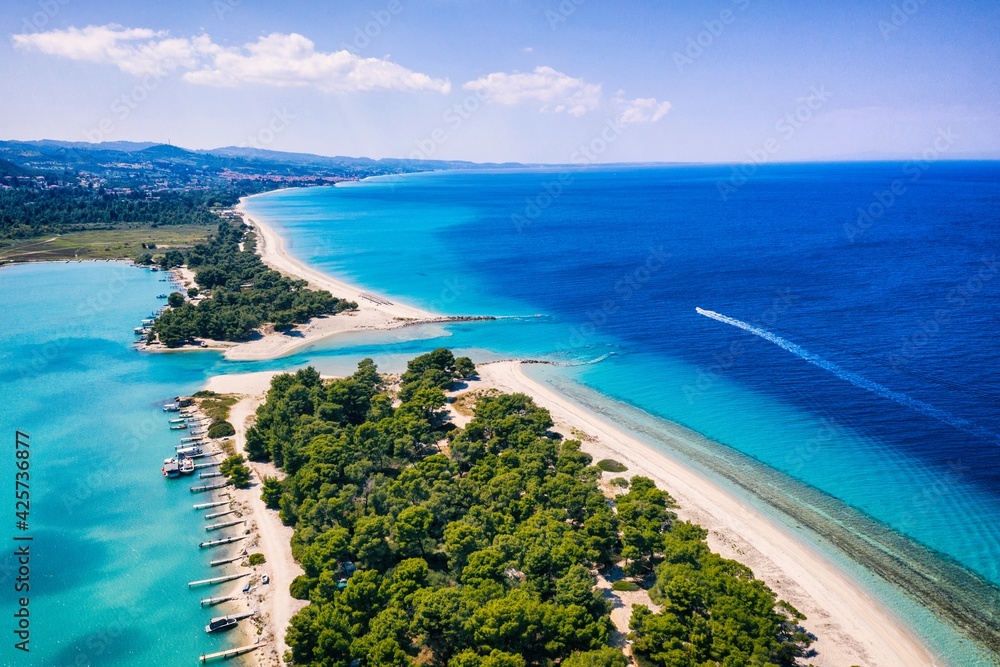 Fototapeta premium Beautiful Beach With Golden Sand And Clear Water. Turquoise coast with blue water and golden sand in Europe. Summer vacation background with turquoise sea water bay and pine trees aerial drone photo