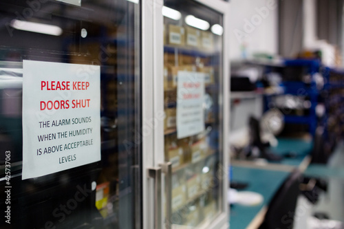 Close up of a sign on a moisture sensitive cabinet in a electronics manufacturer warning people to keep doors closed to protect the raw components inside
