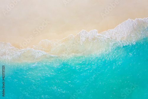 Top view on coast waves on beach aerial view, crystal clear water. Stunning summer landscape, sunny tropical island shore. Seaside, idyllic nature Earth view. Stunning scenery, amazing view