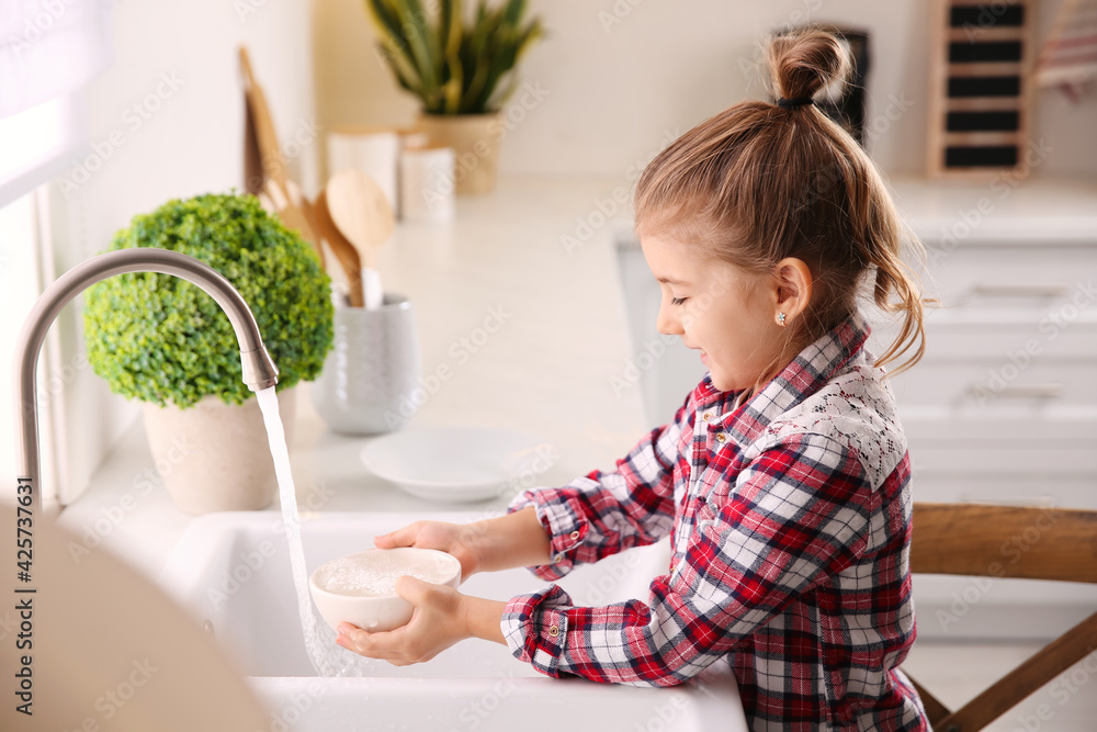 Little girl washing dishes in kitchen at home Little girl washing dishes in kitchen at home