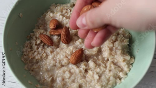 Adding almonds to oatmeal, healthy breakfast close-up