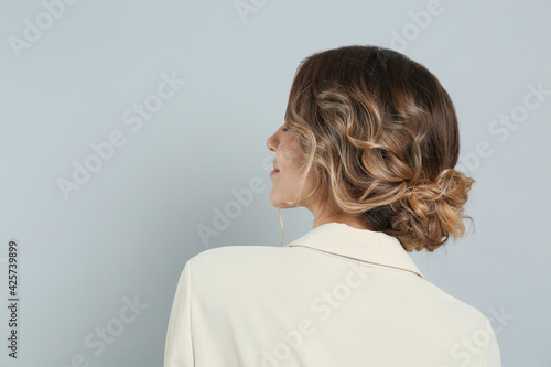 Young woman with beautiful hairstyle on light grey background. Space for text