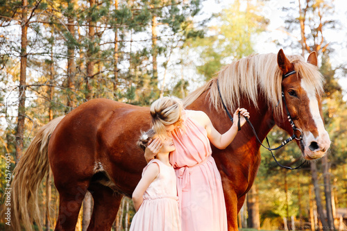 Mom keep the brown horse and kiss daughter.