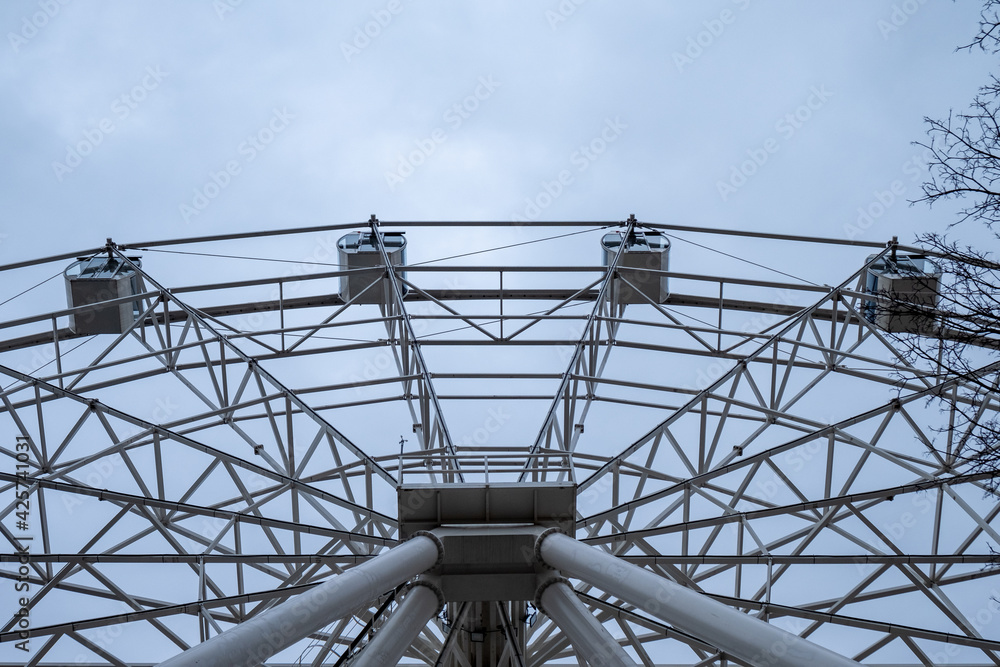 Ferris wheel on a background of a gray sky on a cloudy day. Bottom up view.