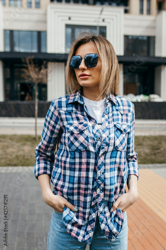 Fashion portrait of beautiful woman with beautiful face, wearing grunge plaid shirt. Posing alone.