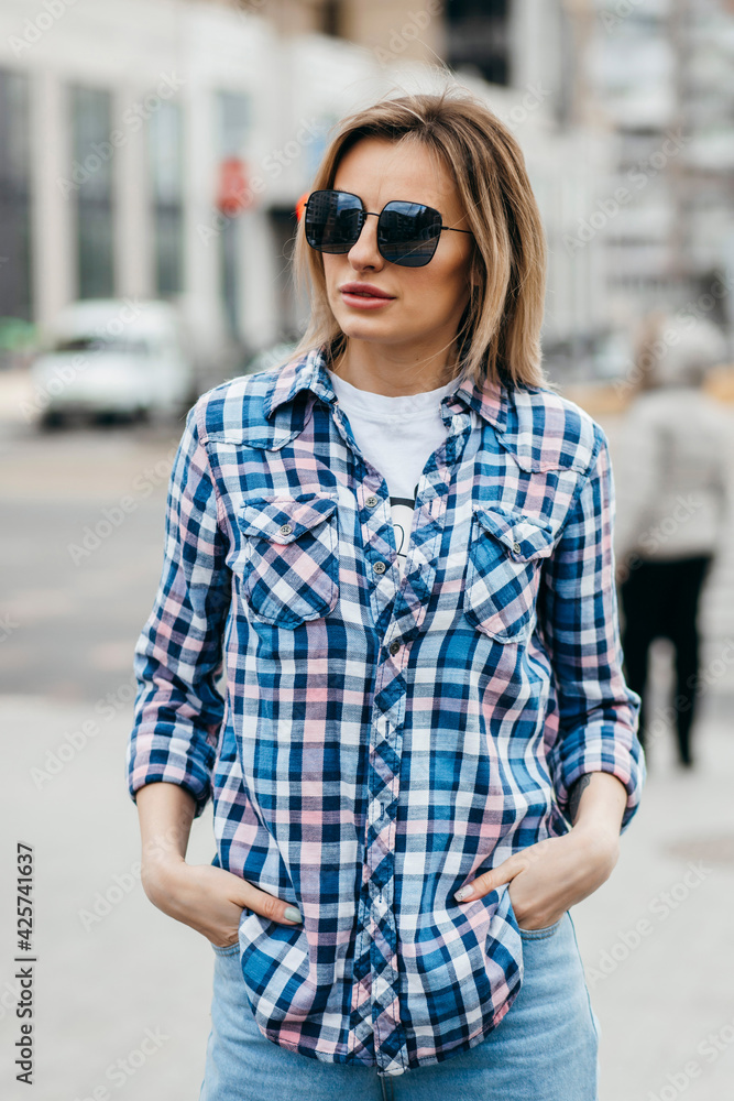 Fashion portrait of beautiful woman with beautiful face, wearing grunge plaid shirt. Posing alone.