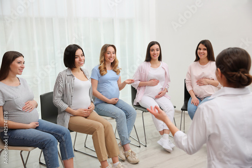 Group of pregnant women with doctor at courses for expectant mothers indoors