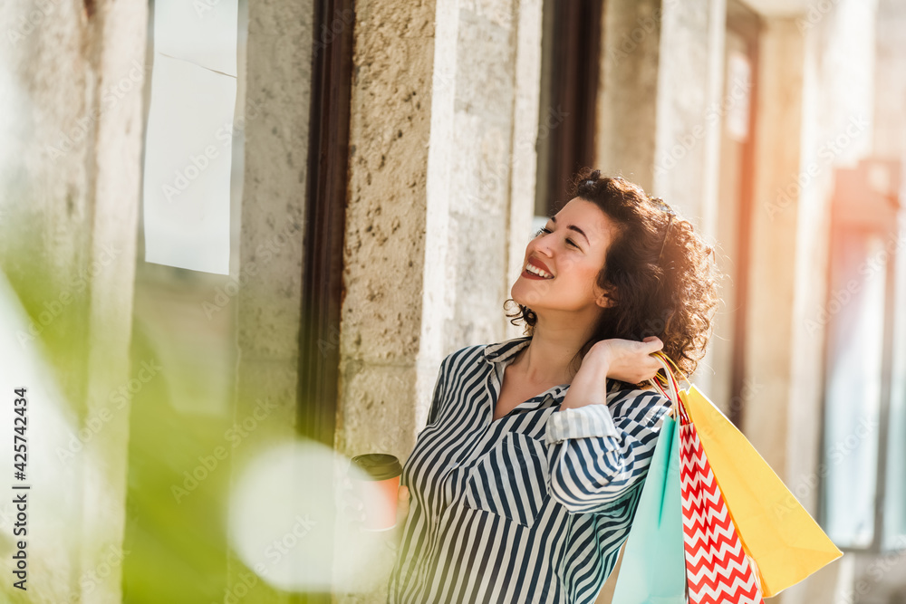 Young woman walk outdoors with coffee cup and shopping bags after shopping Young woman walk outdoors with coffee cup and shopping bags after shopping
