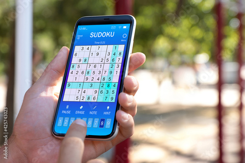 Man playing sudoku game on smartphone outdoors, closeup