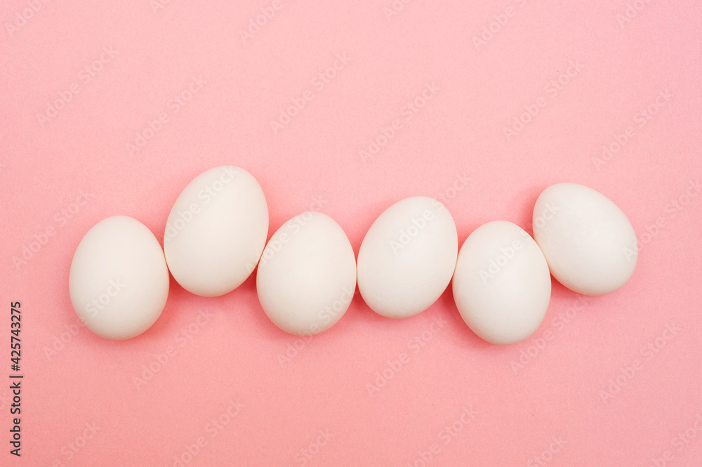 White chicken eggs on pink background
