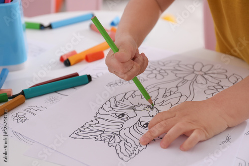 Child coloring drawing at table in room, closeup