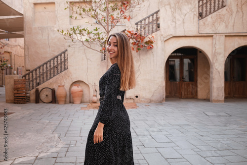 Happy woman traveler wearing black dress walking through the streets