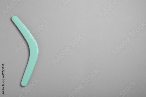 Turquoise wooden boomerang on grey background, top view. Space for text
