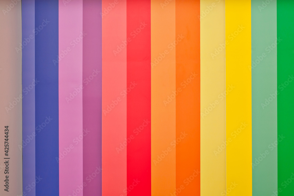 Multicolored strips of paper on the wall. Paper with rainbow colors. Interior design. Multicolored strips of paper on the wall. Paper with rainbow colors. Interior design.