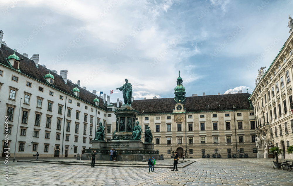 Vienna, Austria - July 13  2019: majestic stone facade of Hofburg, the residence of the emperors of the Austro-Hungarian Empire in Vienna, Austria. A luxurious baroque palace and walking tourists