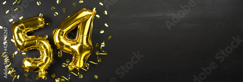 gold foil balloon number fifty four. Birthday or anniversary card with the inscription 54. Black concrete background. Anniversary celebration. Banner. photo