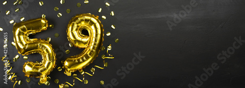 gold foil balloon number fifty nine. Birthday or anniversary card with the inscription 59. Black concrete background. Anniversary celebration. Banner. photo