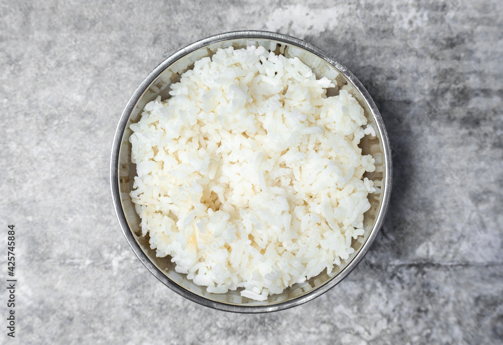 Top view steamed rice in stainless bowl on the gray concrete table. Top view steamed rice in stainless bowl on the gray concrete table.