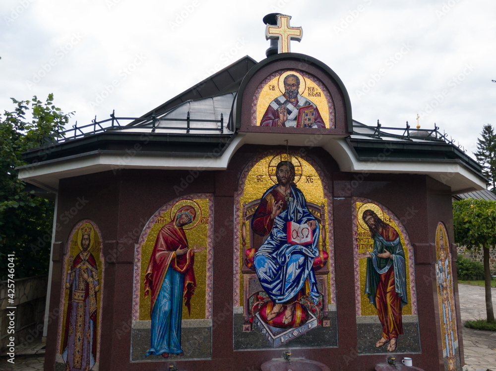 Fototapeta premium Faucet with icons of saints in yard of monastery Ozren dedicated to Saint Nicholas, serbian orthodox temple in village Kaludjerica, Petrovac municipality on mountain Ozren, Bosnia and Herzegovina