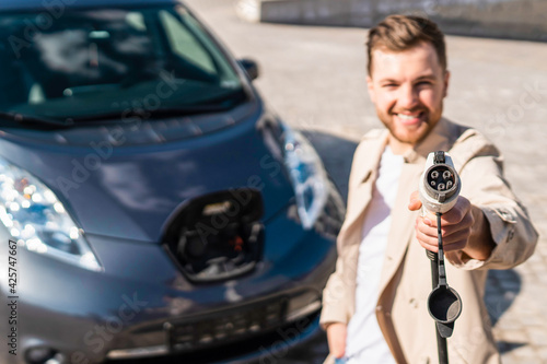 Man shows plug for charging electric cars into the camera